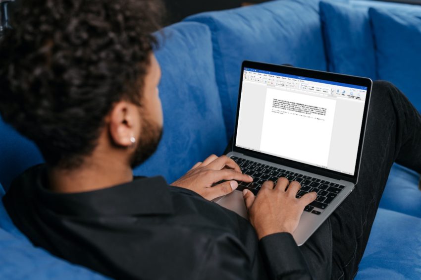 african american man on blue couch typing